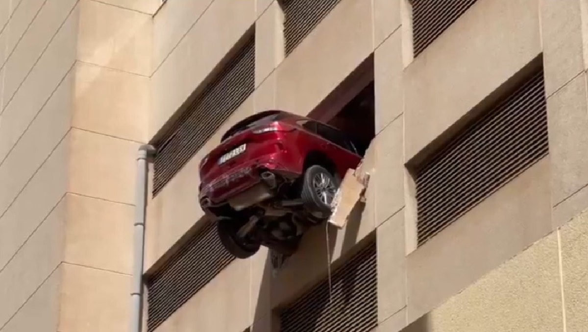 Conductora se echa de reversa, rompe muro y auto queda colgando de un tercer piso